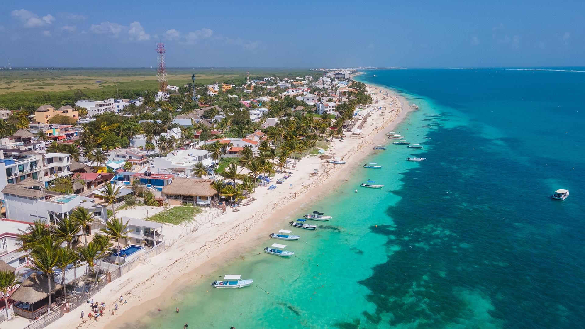 Vue aérienne de Puerto Morelos au Mexique, un village côtier paisible bordé d’eau turquoise et de plages de sable clair.