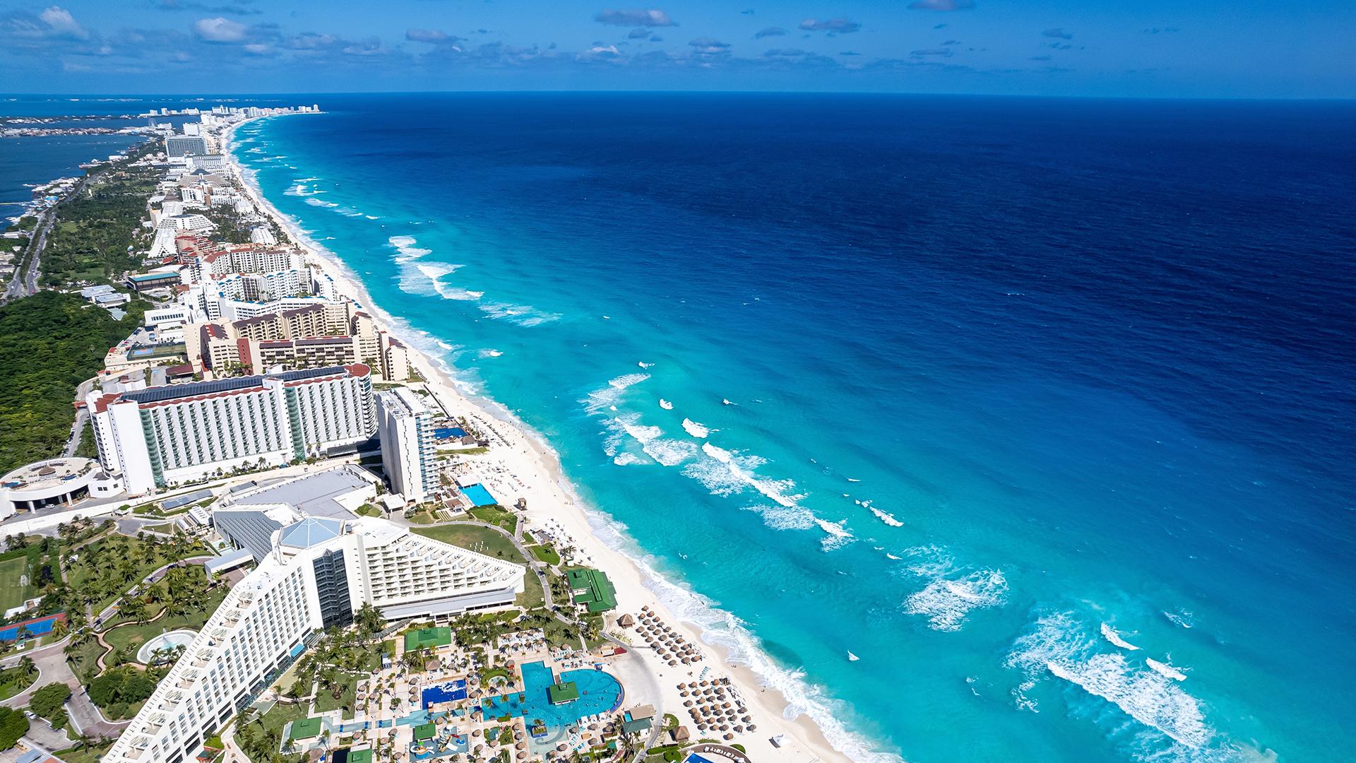 Vue aérienne de Cancún, ses hôtels modernes en bord de mer et ses eaux turquoise éclatantes sous le soleil des Caraïbes.