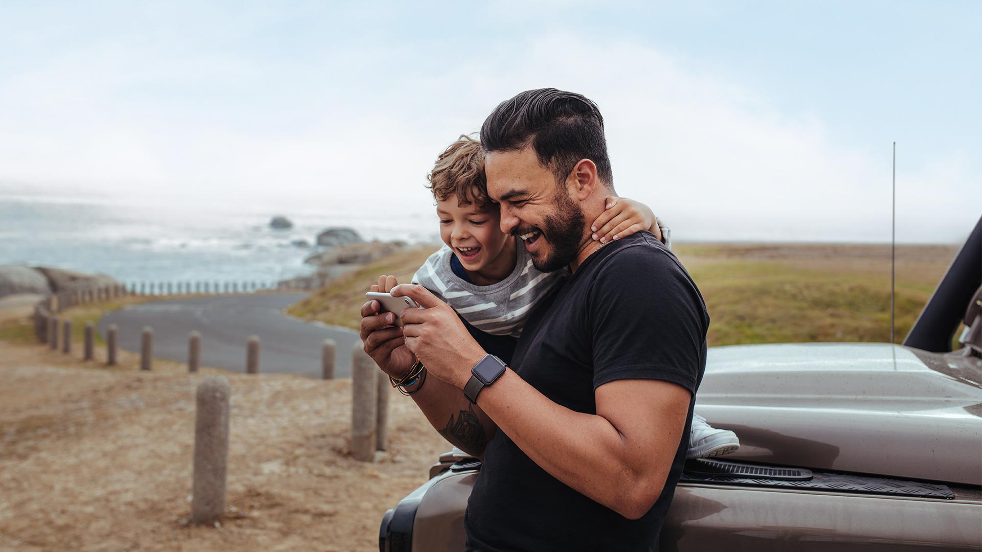 Un homme et une femme sourient, à bord de leur véhicule. A man and a woman sit smiling in their vehicle.