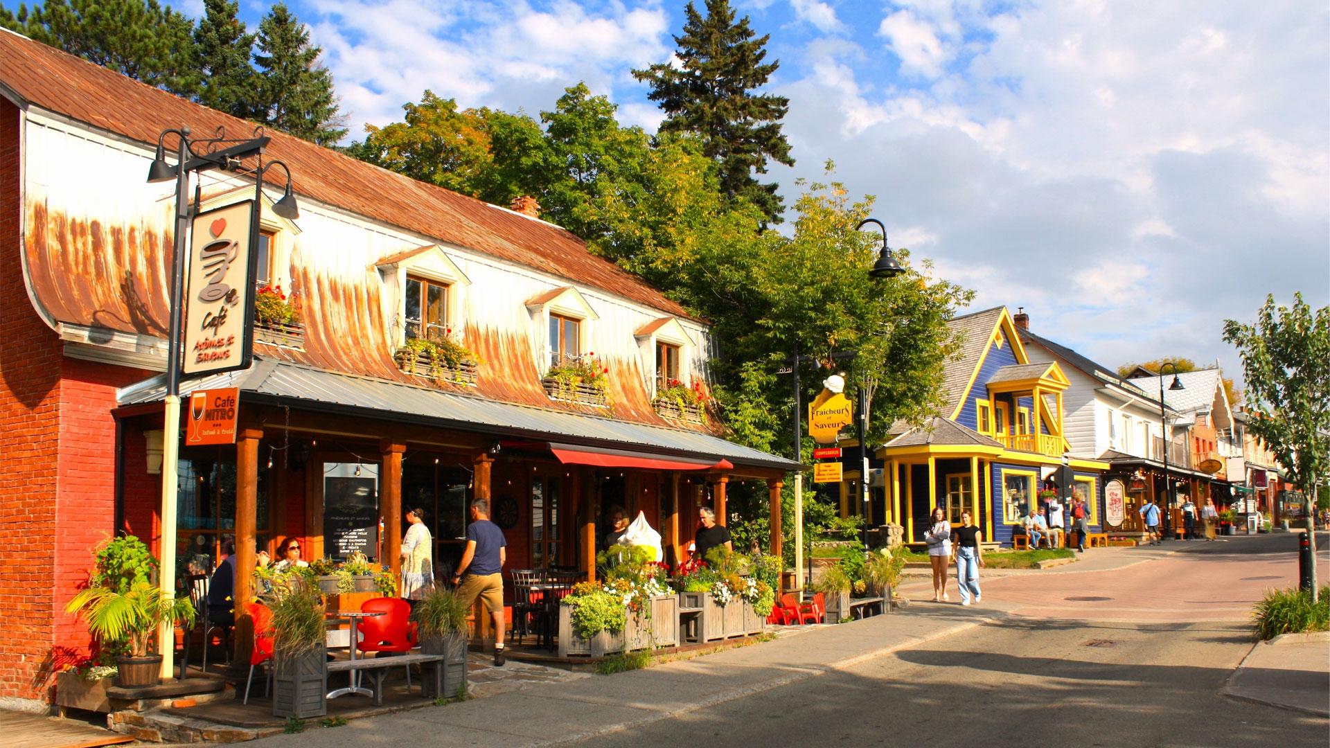Saint-Jean-Baptiste Street in downtown Baie-Saint-Paul, with cafés and colourful façades in a summer atmosphere.