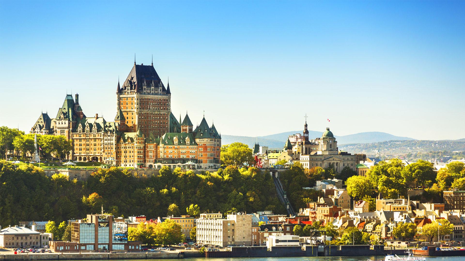 View of Quebec City with Le Chateau Frontenac rising above the trees and the buildings lining the St. Lawrence River.