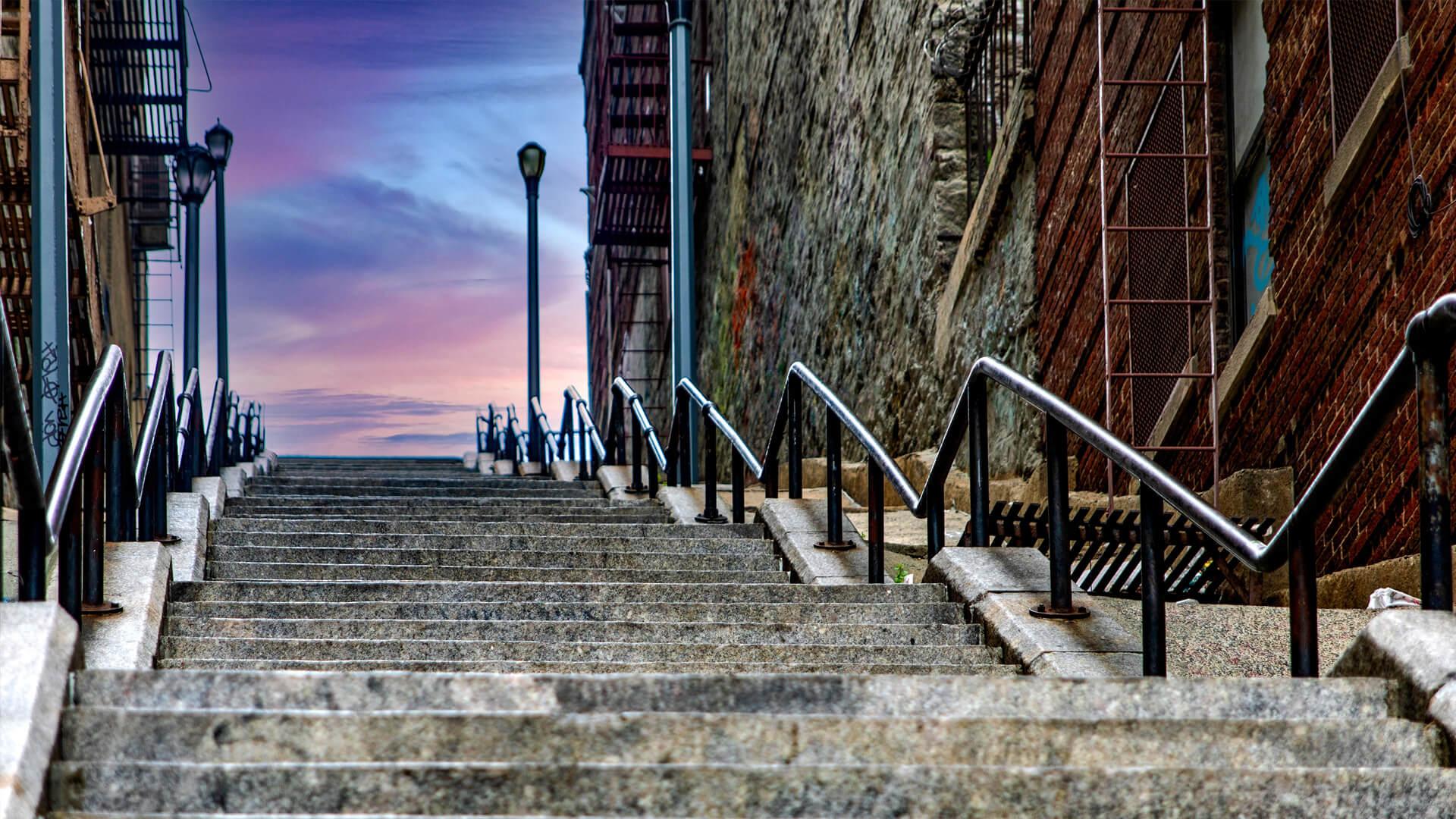Escalier emblématique en pierre dans le Bronx, à New York, au coucher du soleil, entre murs de briques et rampes métalliques.