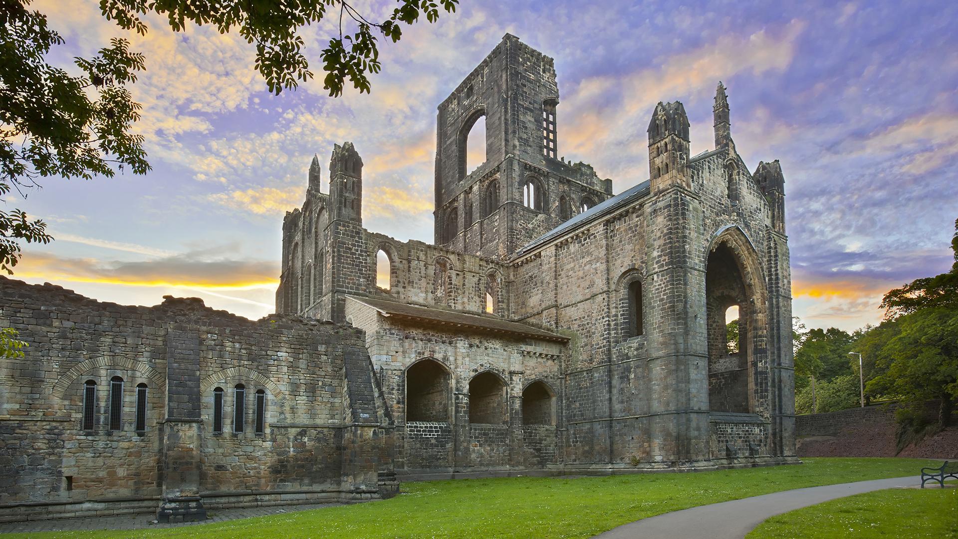 Ruines de l’abbaye médiévale de Kirkstall à Leeds, en Angleterre, entourées de verdure au coucher du soleil.