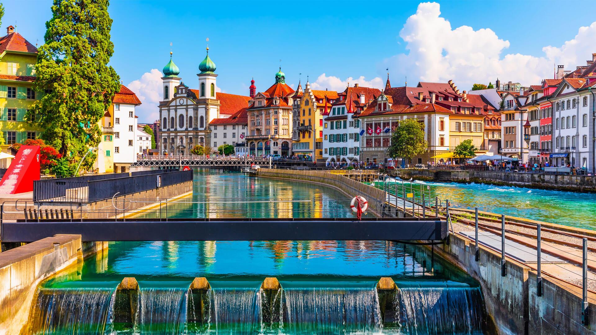 Lucerne, Switzerland, with the Reuss River, Kapellbrücke Bridge, colourful building façades, and St. Peter’s Church.