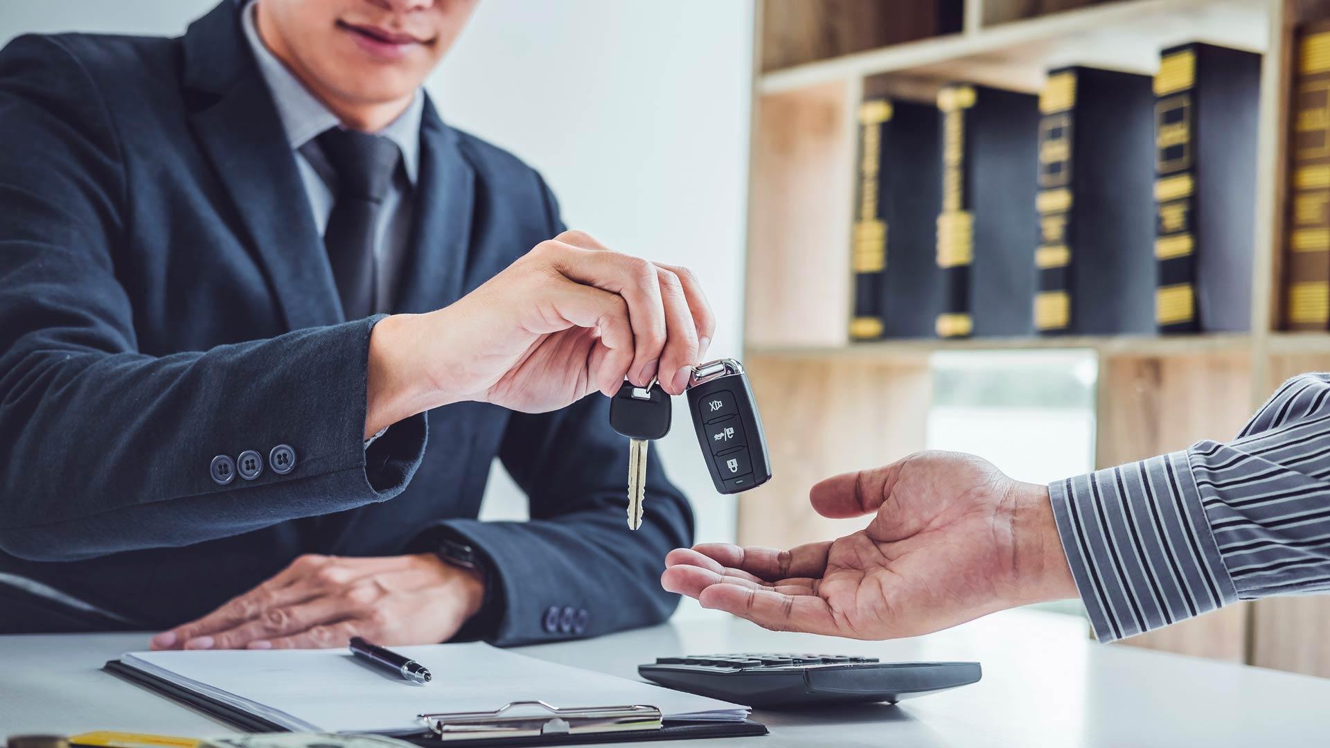 Main d’un homme donnant les clés d’une voiture de location à une autre personne.