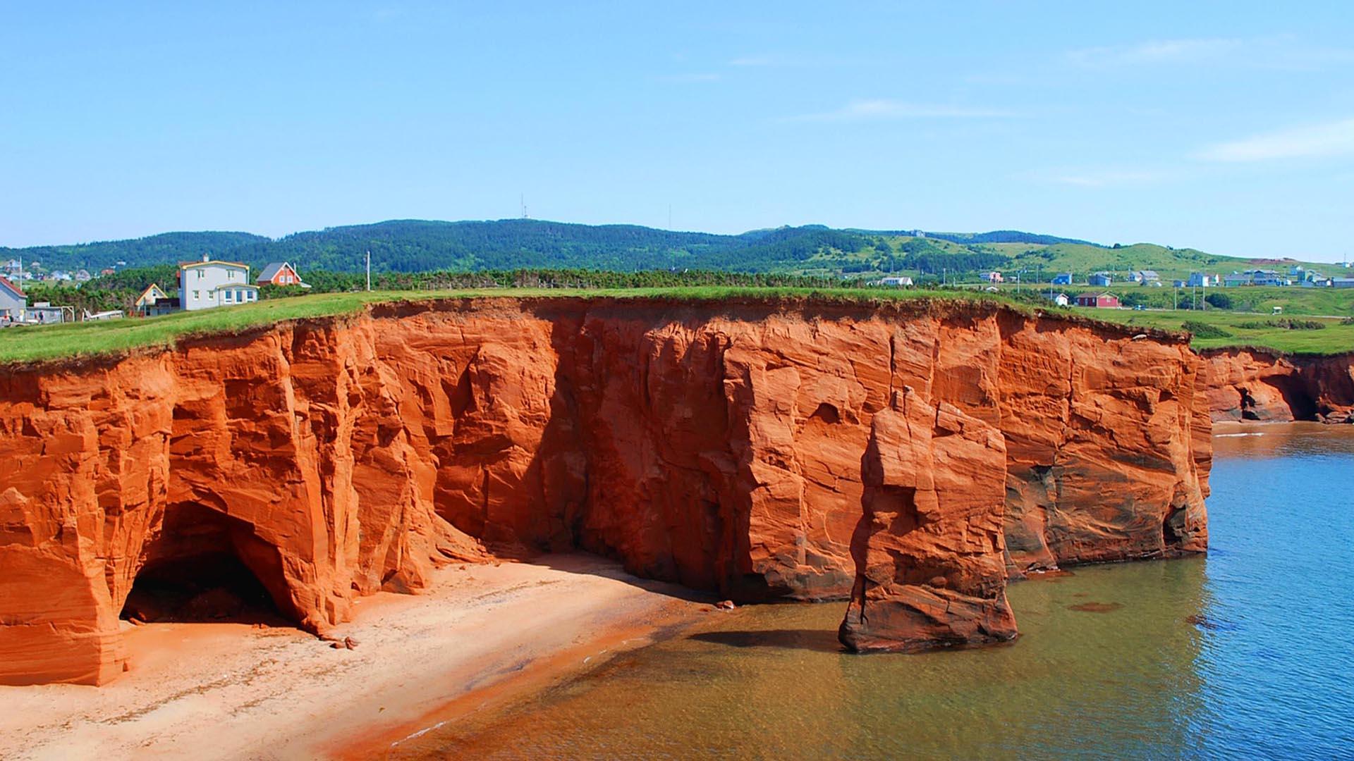 Falaises rouges et grotte en bord de mer aux îles de la Madeleine et plage en bordure du golfe du Saint-Laurent.