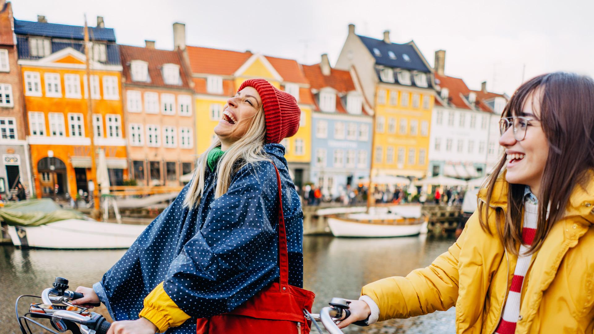 En voyage en Europe, deux jeunes femmes se promènent à vélo au bord de l’eau.
