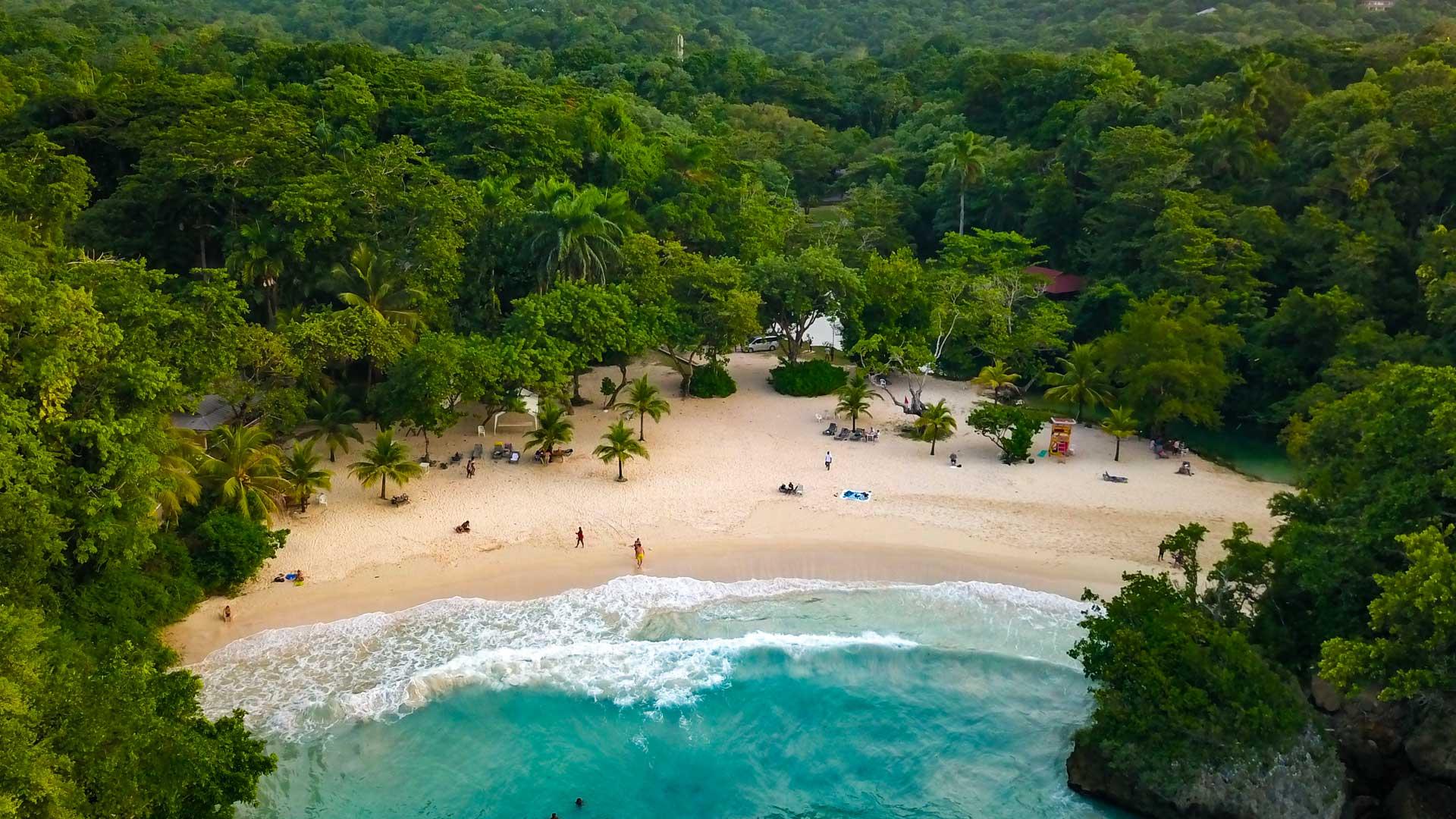 Aerial view of the idyllic Frenchman’s Cove beach in Jamaica, with white sand, turquoise waters, and lush tropical vegetation.