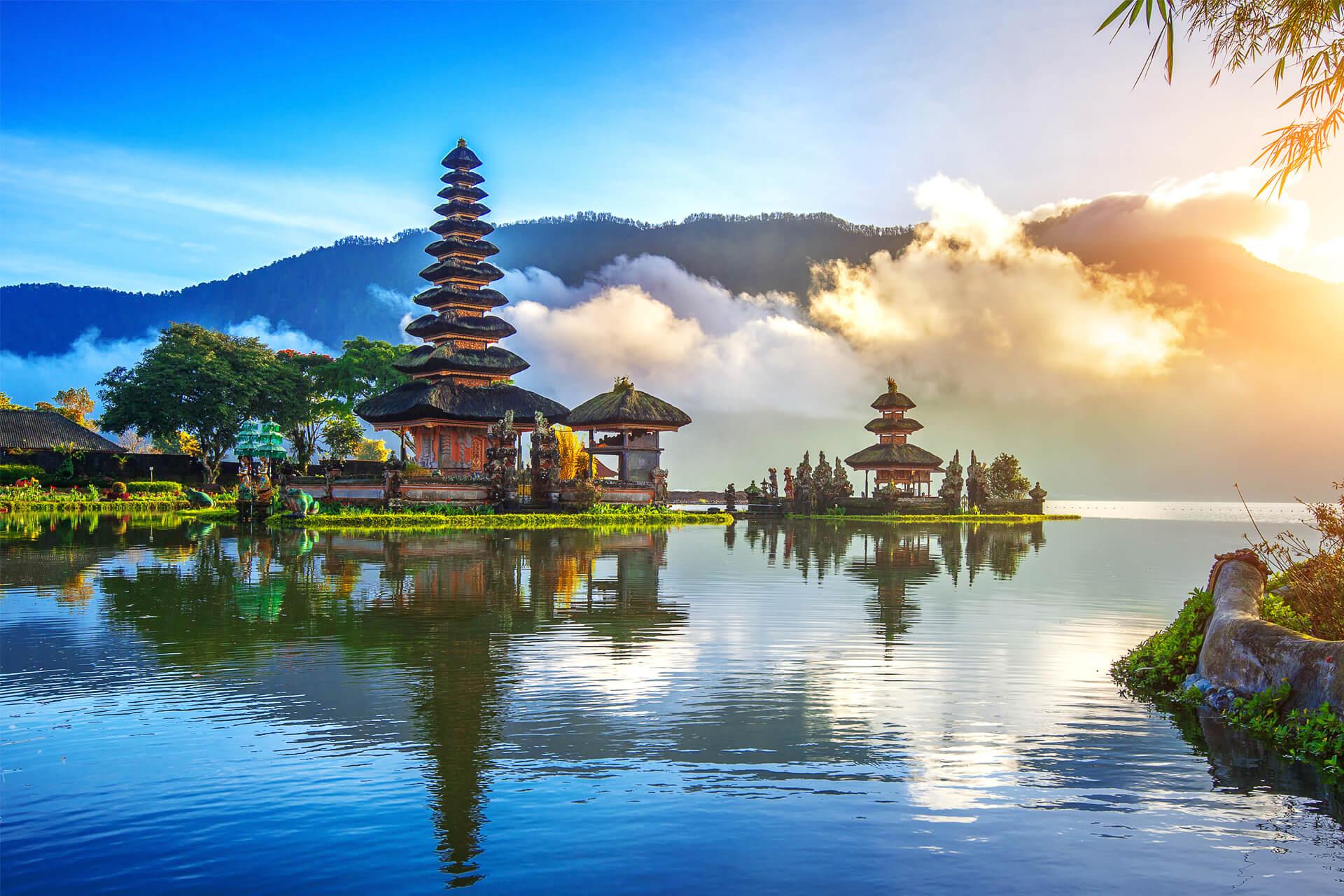 Temple Ulun Danu Bratan sur les rives du lac Bratan à Bali, en Indonésie, entouré de collines enveloppées de brume au lever du soleil.