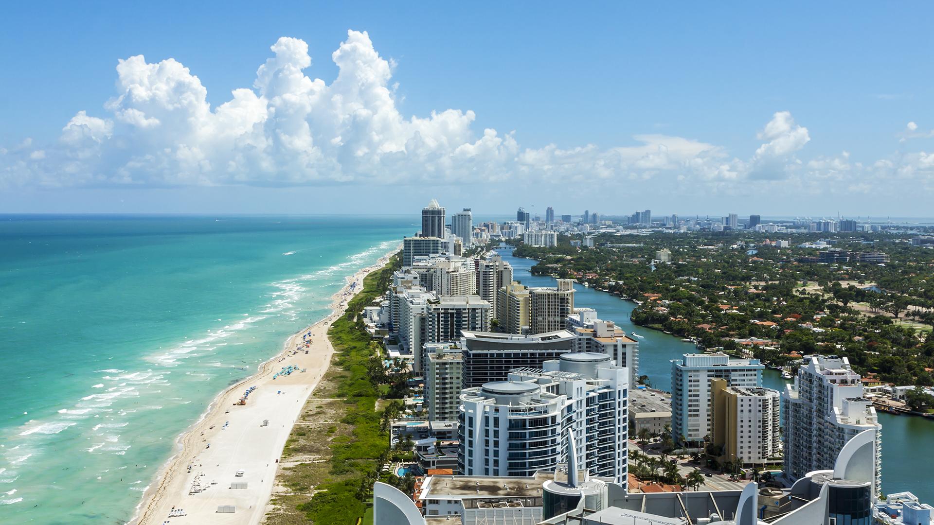 Vue aérienne de Miami en Floride avec plage de sable blanc, eau turquoise et gratte-ciels bordant l’océan Atlantique.