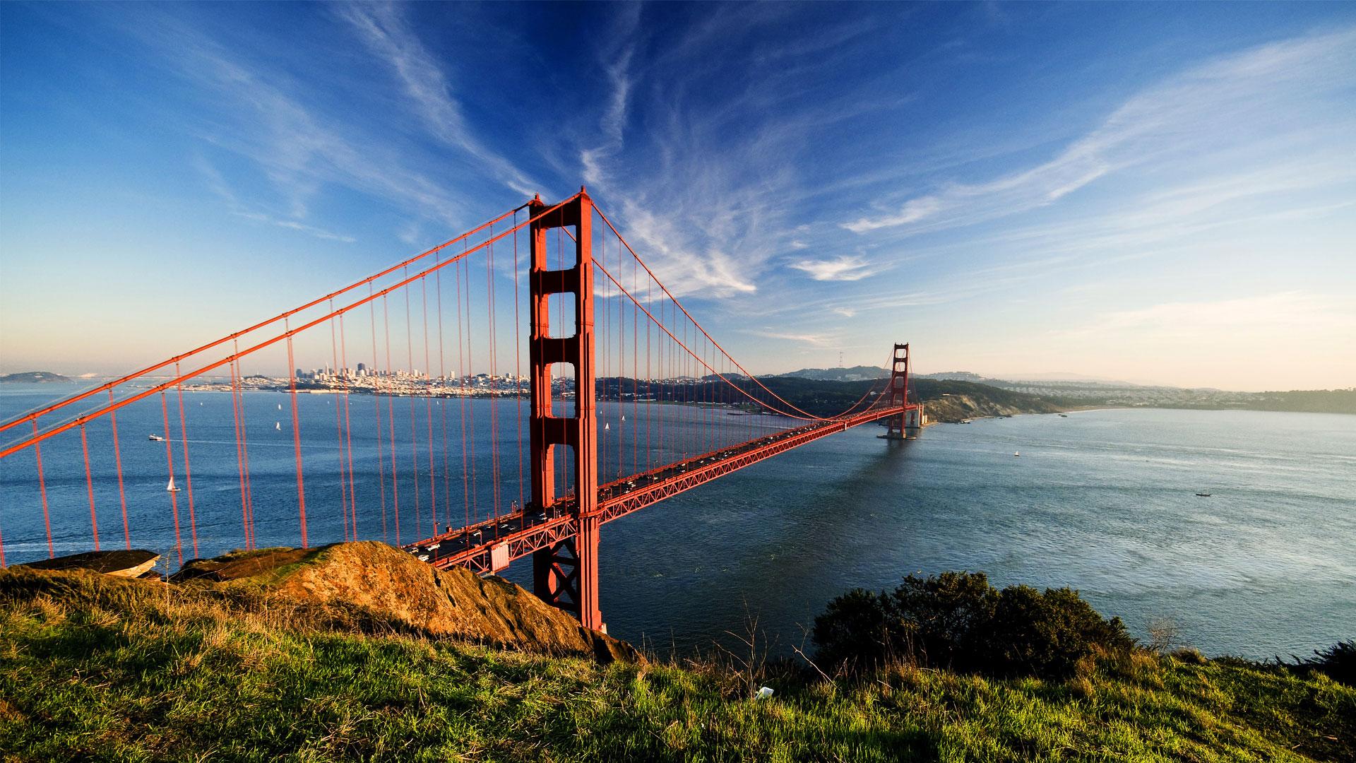 Golden Gate Bridge rouge orangé au-dessus de la baie de San Francisco, sous un ciel bleu nuageux, en Californie.