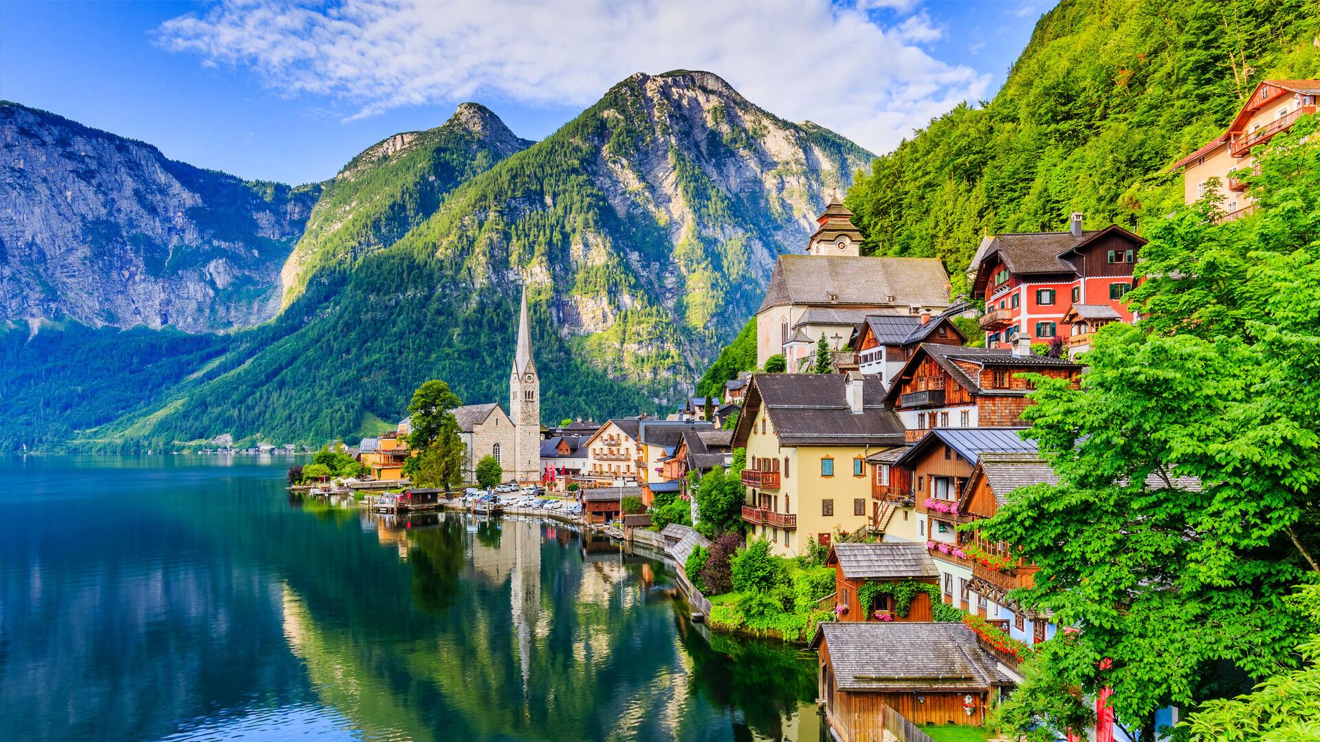 Picturesque village of Hallstatt, Austria, with colourful houses and a church by the lake, framed by Alpine mountains.