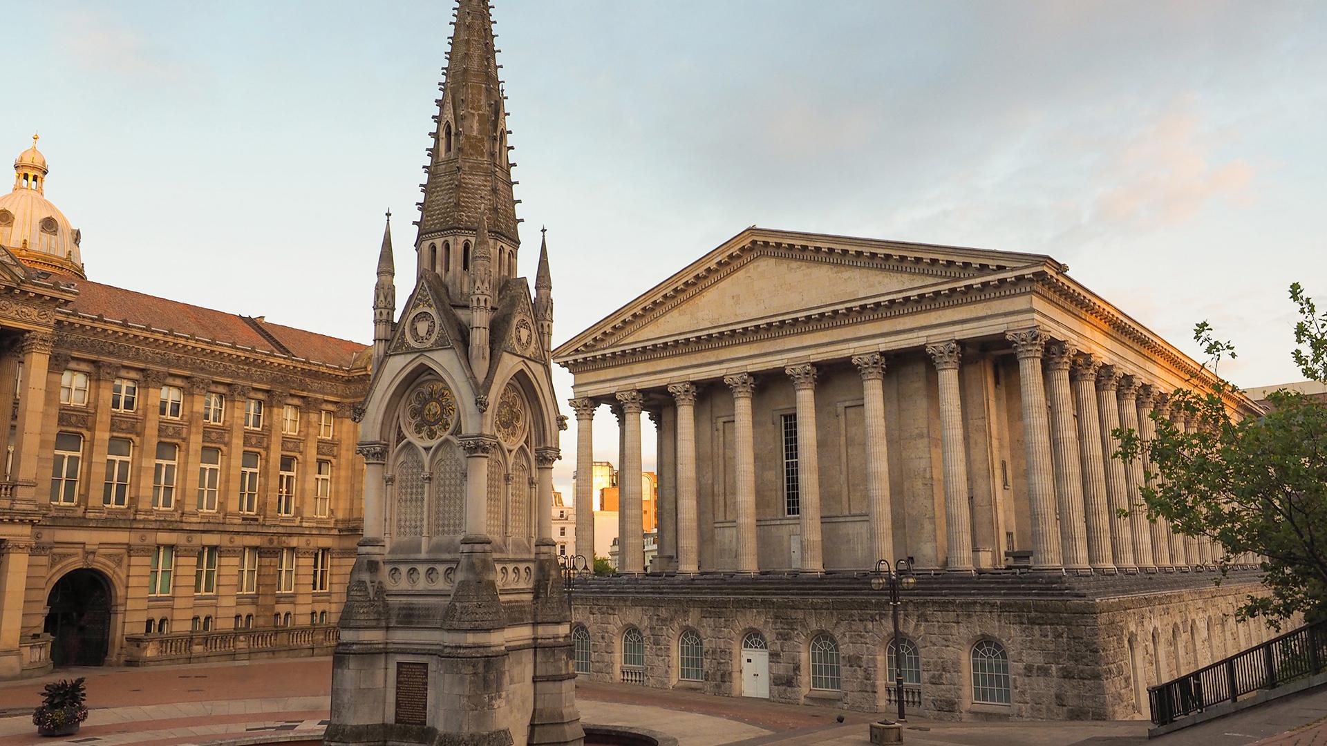 Vue de Chamberlain Square à Birmingham, avec sa fontaine commémorative et le Birmingham Town Hall au soleil couchant.