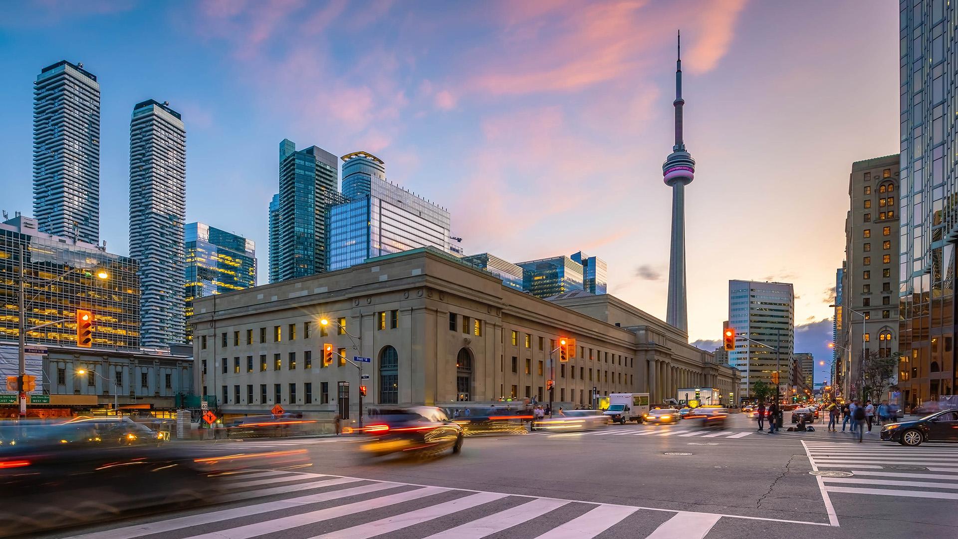 Vue panoramique de Toronto, Ontario, avec la Tour CN, des gratte-ciel modernes, Union Station et une circulation animée au crépuscule.