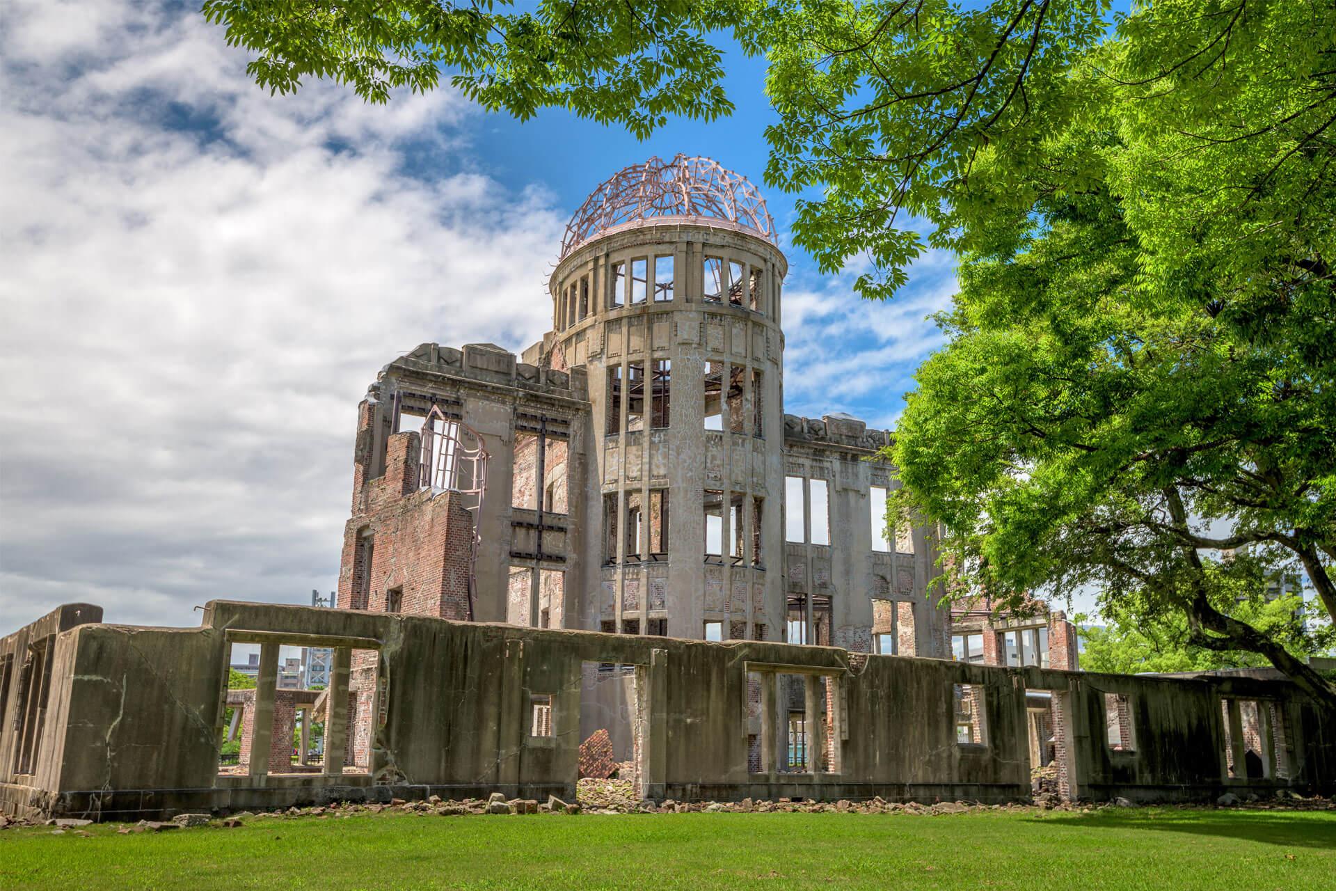 Ruines du dôme de Genbaku dans le parc de la Paix à Hiroshima, au Japon, entourées d’arbres verdoyants.