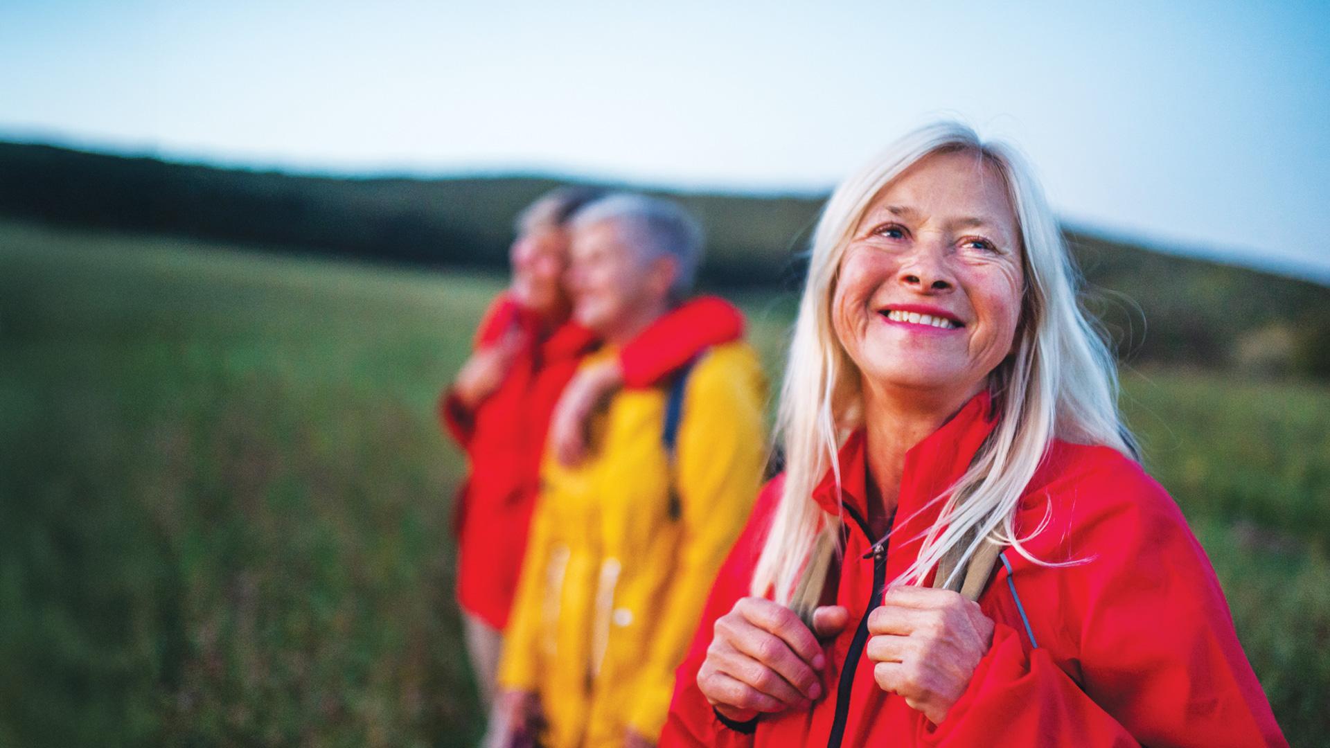 In a picturesque landscape, close-up of a smiling woman taking part in a group trip.
