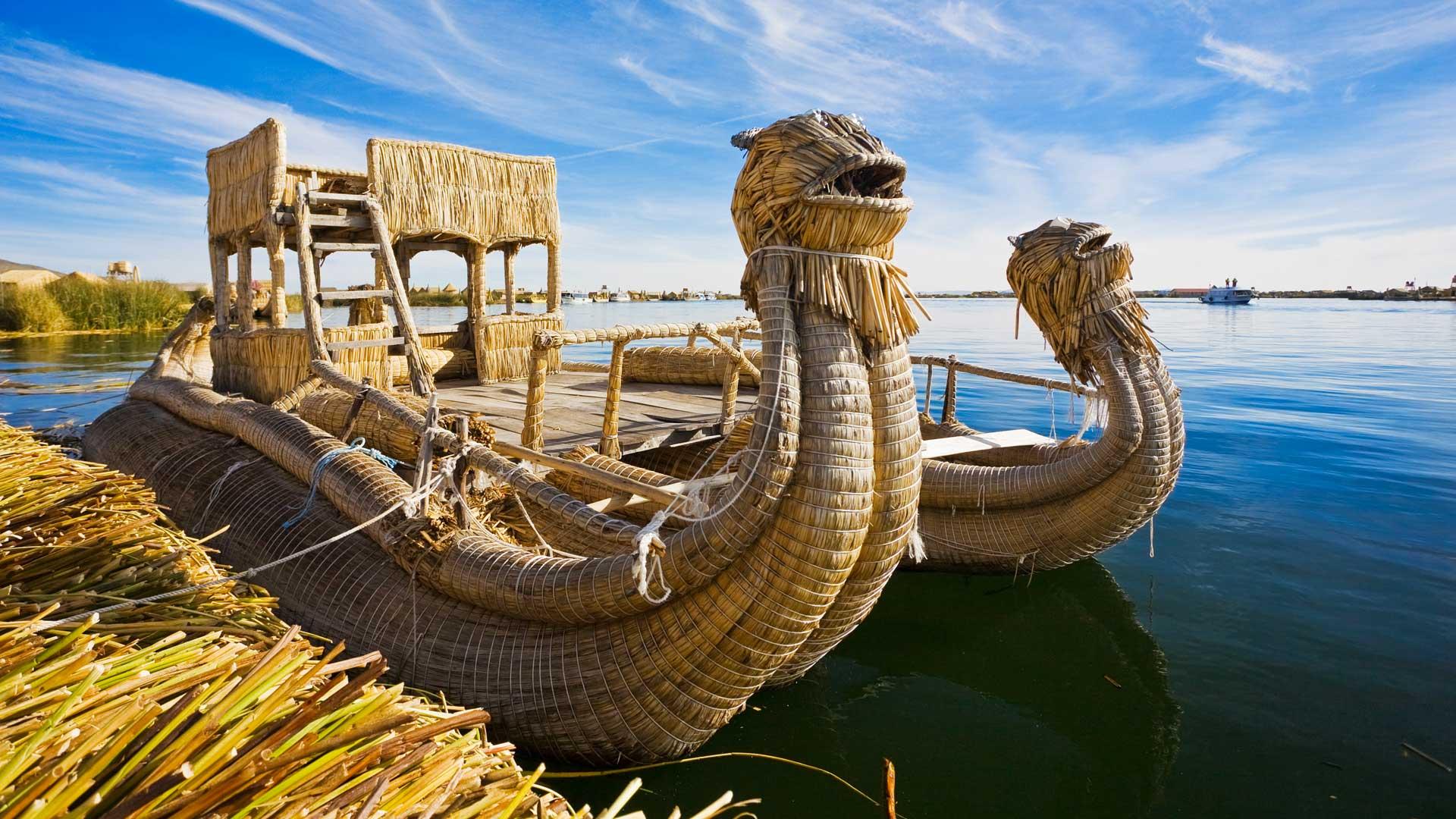 Traditional totora reed boat on Lake Titicaca, Peru, animal-shaped and golden in colour, floating near the shore.
