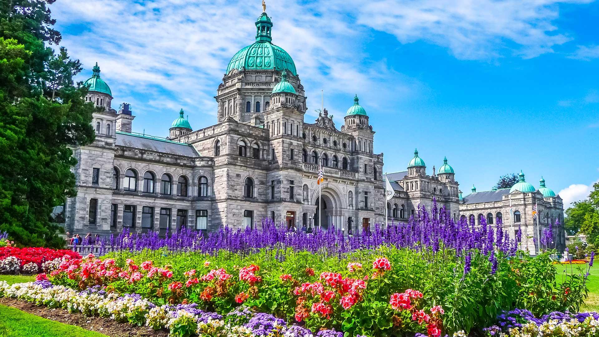 Bâtiment néo-baroque du Parlement de la Colombie-Britannique à Victoria avec jardins fleuris au premier plan.